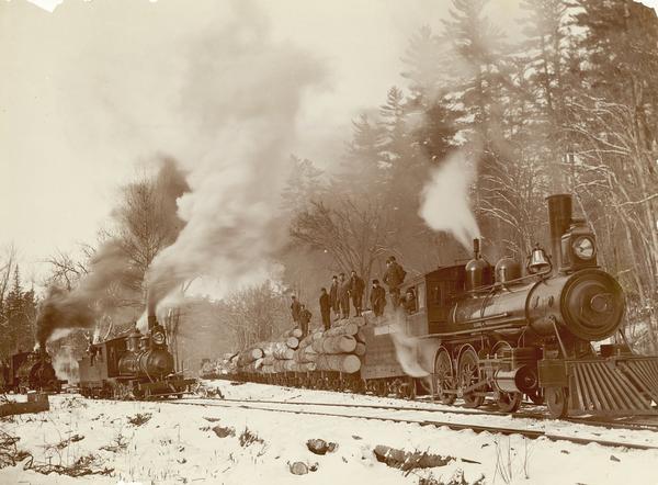 Holmes Sons logging railroad ready to start for landing.  Three steam engines pictured.  Primary engine pulls flatbed cars loaded with logs.