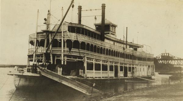 The sternwheel packet, <i>G.W. Hill</i>, docked with its gangplank lowered and no one on deck. Later named <i>Island Maid</i>. There is a bridge in the background on the right.
