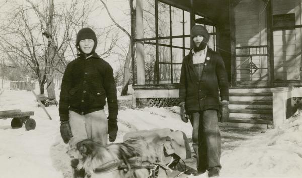 Gaylord Nelson and Sherman Benson as boys in front of the Nelson home during the winter with a dog and sled.