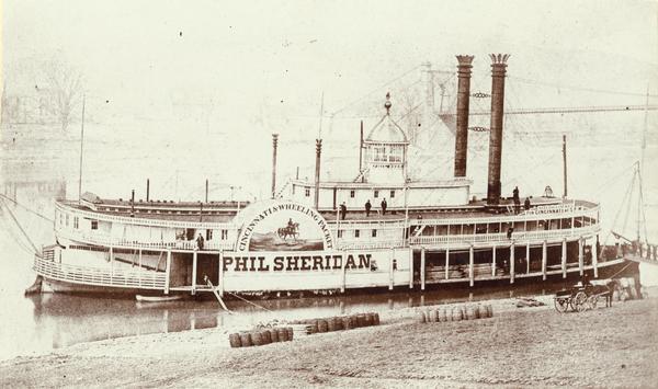 The sidewheel excursion, <i>Phil Sheridan</i>, at Wheeling, West Virginia in March, 1866. Sign on side of boat reads: "Cincinnati and Wheeling Packet, Phil Sheridan." Barrels are the on shore in the foreground.