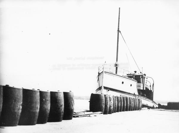 The screw ferry, "Wisconsin," docked at Washington Island. Twenty-one metal drums line the edge of the dock in the foreground. Original is in scrapbook on loan from Haldor Gudmundsen of Washington Island.