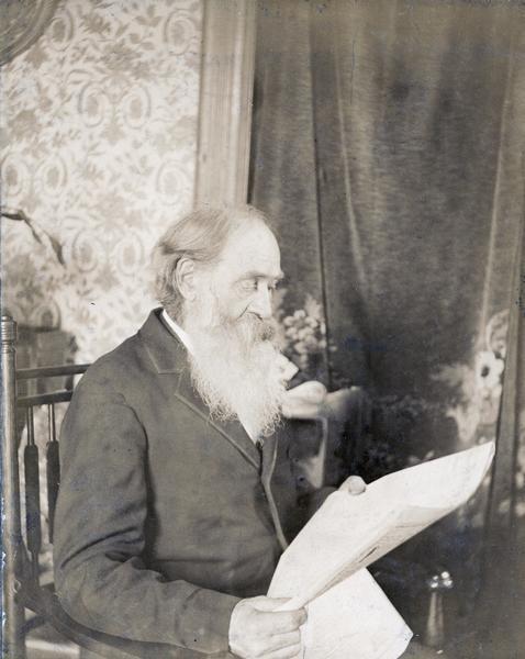 Sherman M. Booth, anti-slavery editor, shown seated reading newspaper.