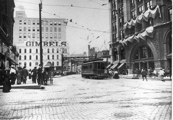 An electric streetcar in Milwaukee with a large Gimbels sign in the background.