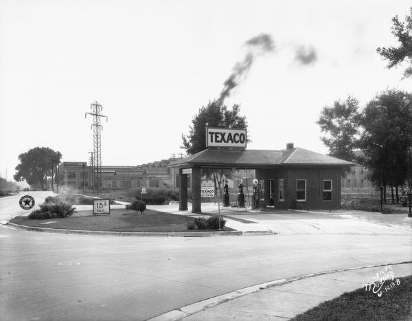 Bondi & Sachtjen Texaco service station, 1462 E. Washington Avenue at Thornton Avenue, with Fuller & Johnson buildings in the background. Text with print reads: "Bondi & Schtjen Texaco Stsation, 1462 E. Washington Avenue. View looking toward Capitol. Fuller & Johnson Mfg. Co., 1402-44 E. Wash. Ave."