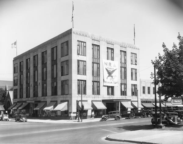 The Harry S. Manchester building, 2-6 E. Mifflin Street, with a large National Recovery Administration banner which reads: "N.R.A. Member - We Do Our Part." Also seen is the Walk-Over Shoe Store, Moseley's Book Store and Kinney Shoes.