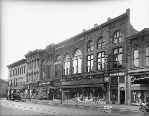 View of East Main Street businesses: Burdick & Murray Co. at 15-17-19 East Main Street, Feltman and Curme, Tailors, 21 East Main Street, Uphoffs Coffee Shop, 13 East Main Street, and Millers Women's Apparel, 23 East Main Street.