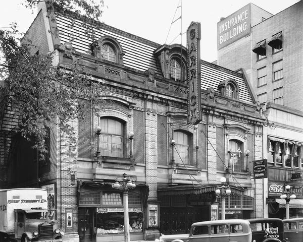 Exterior view of the Garrick Theater at 115 Monona Avenue. The view also contains the Kehoe Cigars store, Savidusky's at 113 Monona Avenue, Jimmy Dodge Billiards & Restaurant at 117 Monona Avenue, and a Motor Transport Co. truck.