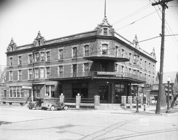 Exterior view from the street of The Hotel Washington, 636 West Washington Avenue, with two cars parked in front.