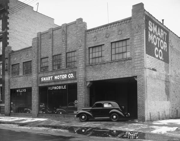 The Smart Motor Company dealership located at 437 West Gilman Street, designed by Harry Alford. Signs in the show windows read: "Willys" and "Hupmobile."