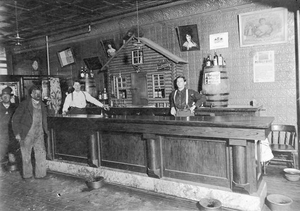 Interior of bar with two bartenders and customers standing at the bar.