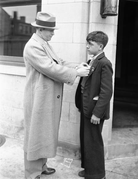 Captain Leo Kinney, Captain of Detectives, pinning a detective's badge on Joe Fedele, member of Post's Junior Detective Club, an organization sponsored by Post Cereal.