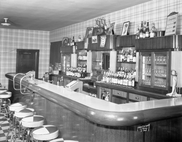 Interior view of DiSalvo's Spaghetti House bar, located at 810 Regent Street in the Greenbush neighborhood. Family portraits, including servicemen, are on wall above the bar, and a service flag with stars.
