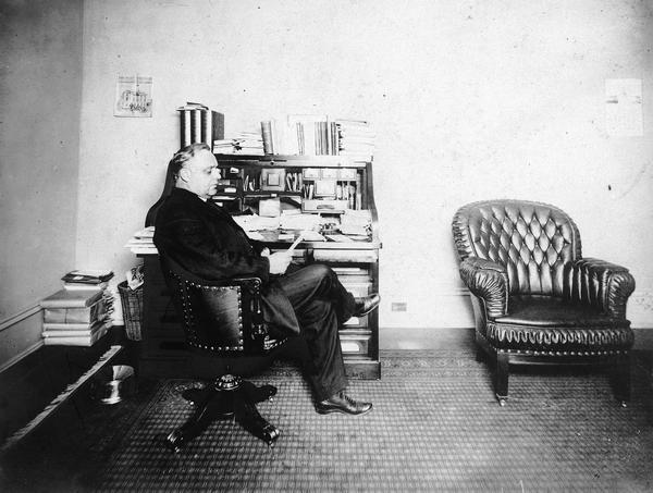 U.S. Congressman of Wisconsin John J. Esch seated at his desk.