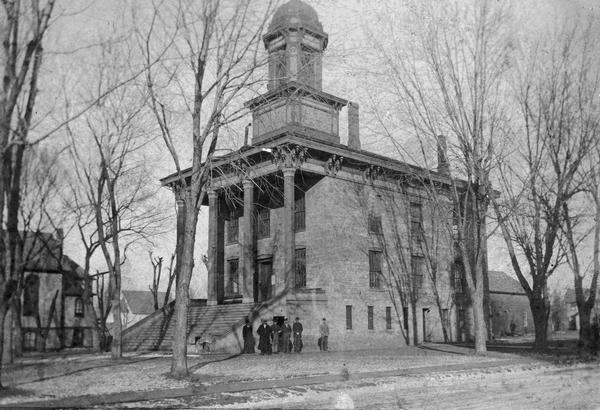 Exterior view of the St. Croix County Court House with six people standing in front of it.
