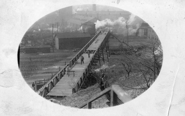 Men walking across a bridge over railroad tracks.