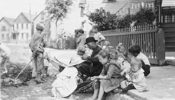 Man sitting outdoors surrounded by children on Pulaski Street.