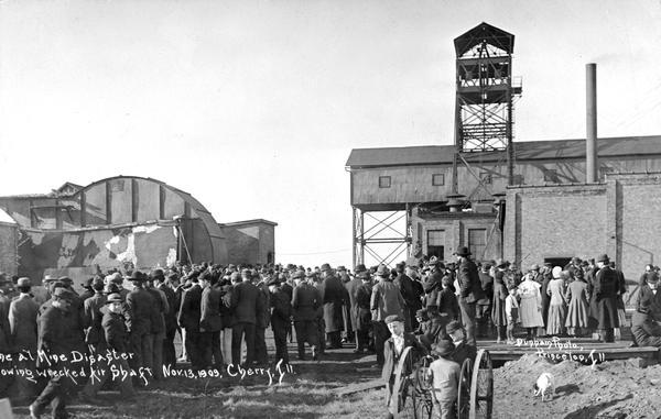 Photographic postcard of people gathering around an air shaft of a mine in after a mining disaster. Caption reads: "(?) at Mine Disaster showing wrecked air shaft, Cherry, Ill."