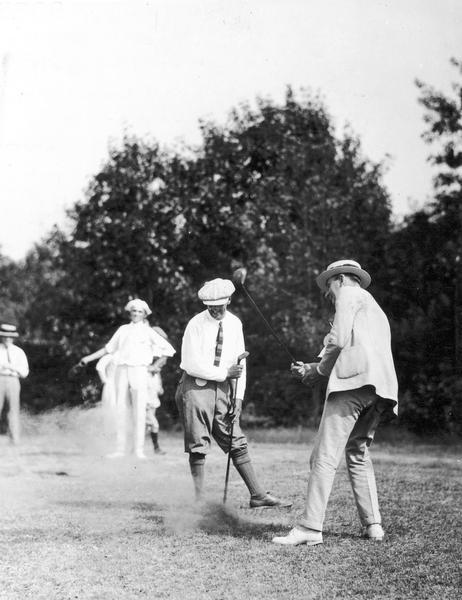 Madison Mayor Milo Kittleson hitting the first tee shot on the temporary nine-hole golf course of the Nakoma Country Club at the formal opening on June 23, 1923 at 2:50 p.m. Nakoma's first golf professional and designer of the temporary course, Albert Edward Mayo is standing to the left of the mayor.
