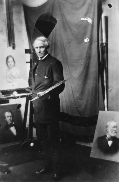 James Reeve Stuart in his studio, with paintings.