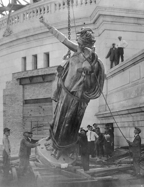 Starting to raise "Wisconsin" statue onto the dome of the Wisconsin State Capitol (the fourth State Capitol, the third in Madison, 1906 - ). The gilded bronze statue is by Daniel Chester French and weighs over 3 tons.