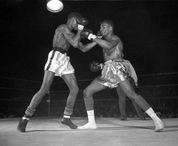 Cassius Marcellus Clay Jr., who later changed his name to Muhammad Ali, (white trunks) fighting Amos Johnson in the 178 pound final of the Pan-American Games boxing trials at the University of Wisconsin-Madison Field House.  Both were 17 years old, Johnson earned a split decision. It was Clay's first loss in 37 fights.