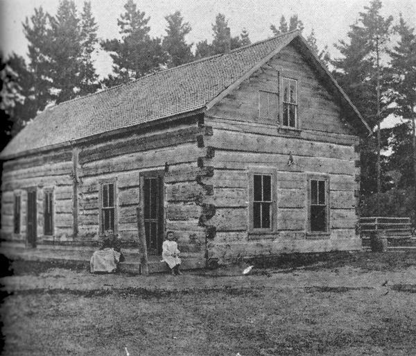 Home of the Thomas Family at Lac Vieux Desert, built in 1860, and housed the Lac Vieux Desert Trading Post. Seated on the doorstep are Mrs. Leonard Thomas, mother of Louis, and her daughter Katie. Lac Vieux Desert is a 4200 acre Michigan-Wisconsin boundary water in Vilas County.