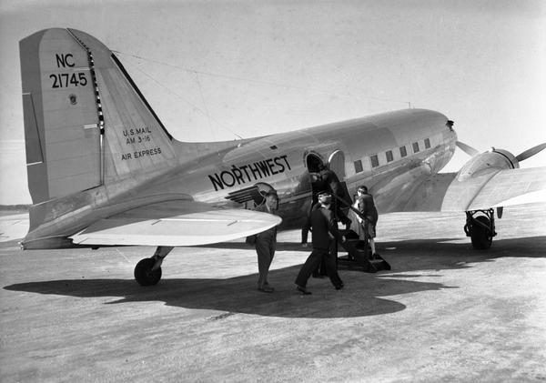 Passengers boarding a Northwest Airlines DC-3 at Madison Municipal Airport. When this airplane was photographed for the WPA by Harold Hone, the DC-3, one of the most important airplanes in the history of commercial aviation, had only recently been introduced by Douglas Aircraft.  Because of their larger passenger loads, DC-3 freed commercial airlines from their dependence on airmail contracts.