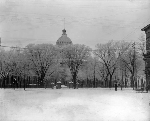 Winter scene of the third Wisconsin State Capitol looking west from King Street. By the turn of the century, the trees in the Capitol had grown tall and only the dome could be seen above them.