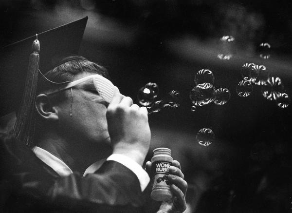 Marquette University graduate blowing bubbles before his graduation ceremony at the Bradley Center.