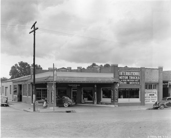 Dealership and service station of Younger Motor Truck Company. A station attendant is putting air in the tire of a car in the service area. Image printed in "From 1 Truck to 257 -- That's Younger's 17-Year Record with International", International Harvester Dealer, January 1939.