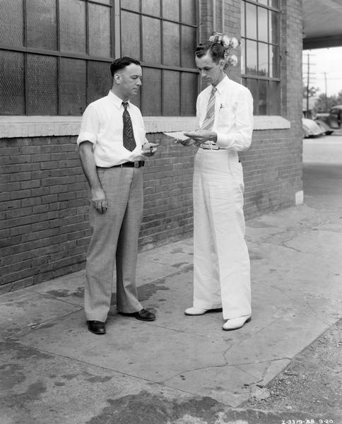 International dealer and a sales promotion man talking things over outside the Younger Motor Truck Company dealership building. The dealer, George Younger is at left. The Shreveport sales promotion man is J.H. Myers. Photograph taken for the article "From 1 Truck to 257 -- That's Younger's 17-Year Record with Internationals," International Harvester Dealer, January 1939.