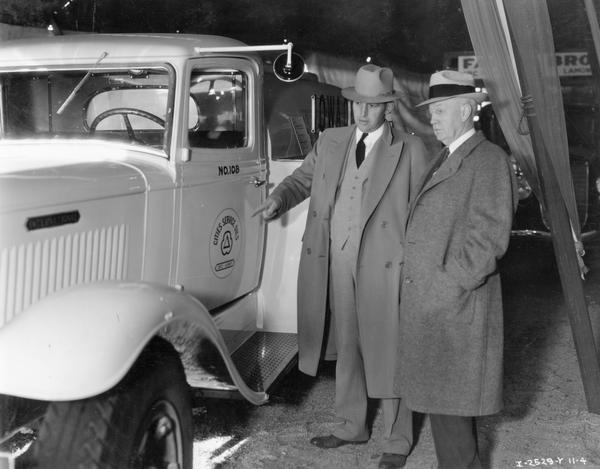 International Harvester assistant manager W.A. Riggs pointing out the features of an International truck to Iowa Governor Clyde Herring, possibly in the display tent of an exhibition or fair.