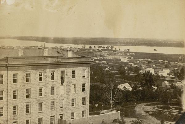 View of Madison from Main Hall, now Bascom Hall, on the University of Wisconsin-Madison campus. South Hall is in the foreground, with several residences and Lake Monona behind.