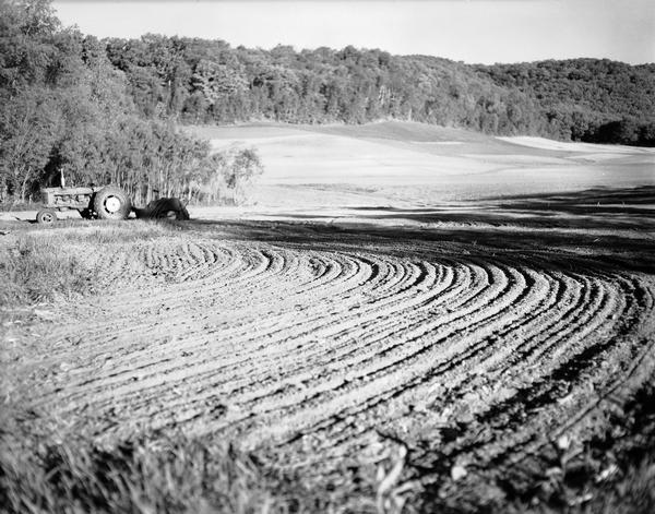 A tractor parked in a newly plowed corner of a field.