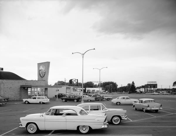 The parking lot of a Piggly Wiggly grocery store (3557 E. Washington) looking northeast toward the corner of East Washington Avenue and Highway 51.   Other businesses include the Serv-U-Beverage store, 3555 E. Washington Ave., the Suburban Corner Texaco gasoline station, 3594 E. Washington Ave. and a Lennox sign on another building.  The Piggly Wiggly became the Casino Lanes bowling alley and then All Star Lanes.  All Star closed in 2002.