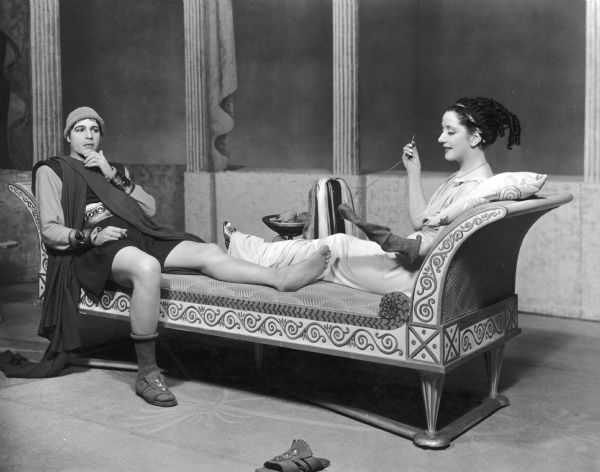 Alfred Lunt and Lynn Fontanne reclining as Lynn's character darns the sock of Lunt's character.