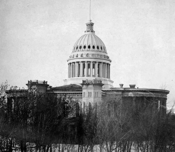 The third Wisconsin State Capitol (second in Madison), surrounded by trees. When construction on the capitol was completed in 1868, the structure measured 228 feet north to south and 226 feet east to west. It set the precedent for a capitol with four roughly equal wings oriented to the points of the compass.