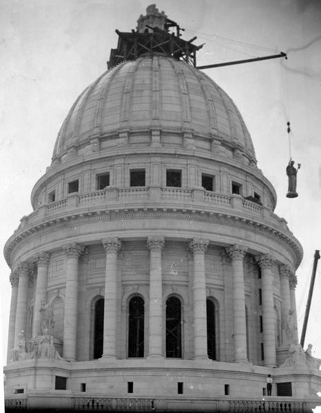 The bronze statue "Wisconsin," by Daniel Chester French, is hoisted to the top of the Wisconsin State Capitol dome.