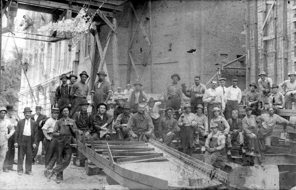 Group portrait of the crew that constructed the Wisconsin State Capitol dome. The new East Wing is visible in the background.