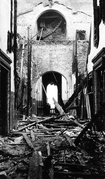 The remains of a second floor corridor in the North Wing of the Third Wisconsin State Capitol after the fire of February 27-28, 1904. This photograph documents the damage near the Rotunda.  Judge John Winslow recalled that the fire stopped short of the octagonal towers in the hallway, so that the portion of the newer portion of the North Wing escaped damage. The upper stairway led from the third floor to the attic over the Senate and Assembly where a sprinkler system had been installed during the Schofield administration. Through human error, the University reservoir that fed the sprinklers was drained shortly before the fire.  Although they are charred in this image, this photograph provides the best extant documentation of the original door framing in the Third Capitol.