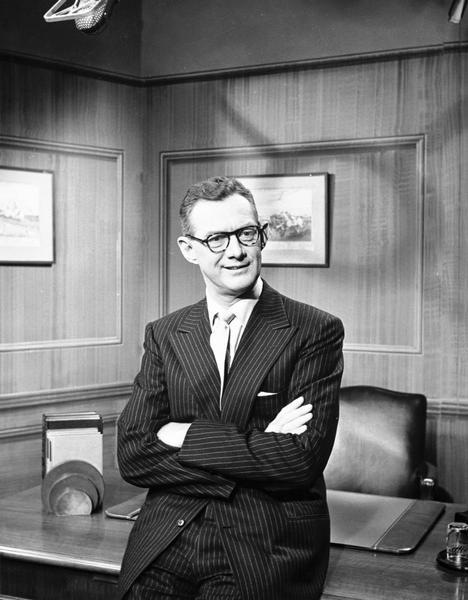 Candid portrait of Sylvester "Pat" Weaver, father of Sigourney Weaver, wearing a pinstripe suit and horn-rimmed eyeglasses, in his office.