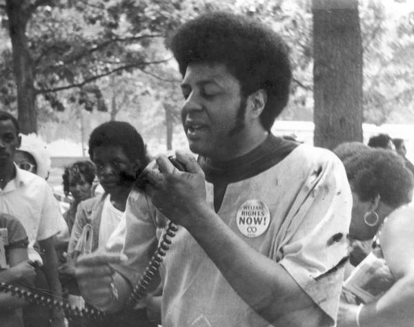 George Wiley speaking at a rally, wearing a "Welfare Rights Now!" button on his shirt.