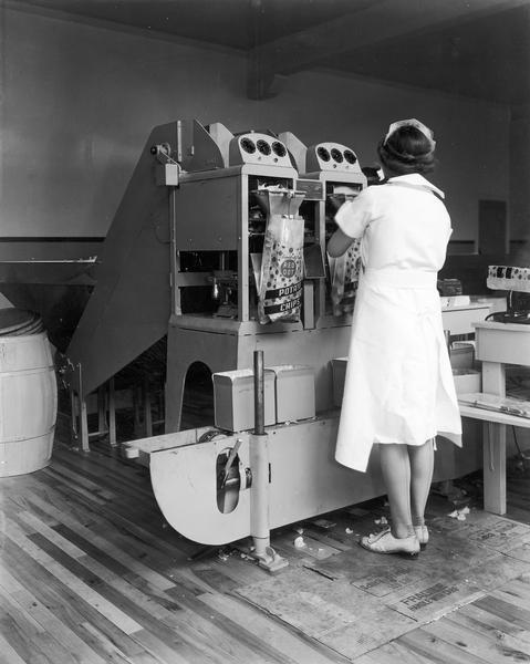 A woman operates the bagging machine at the Red Dot potato chip factory.