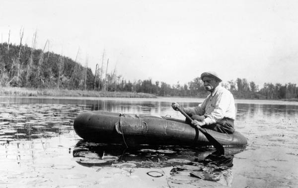 Dr. Edward Ashael Birge paddling on a raft in Trout Lake. In 1875 Dr. Birge first came to teach natural history at the University of Wisconsin, and remained part of the institution for the next 75 years.