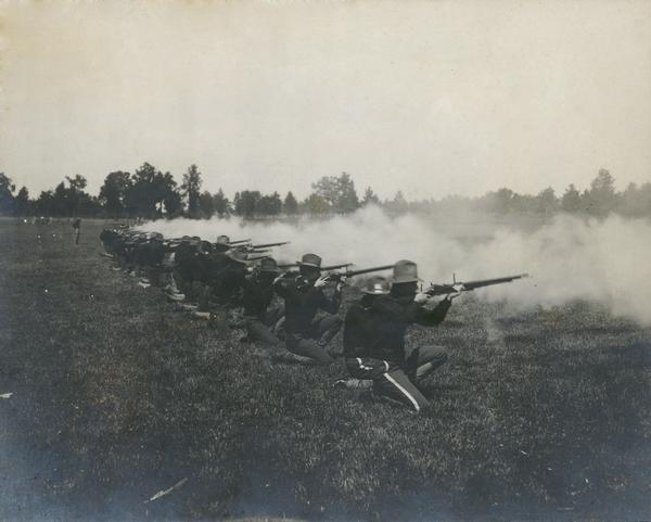Row of soldiers on one knee firing rifles.