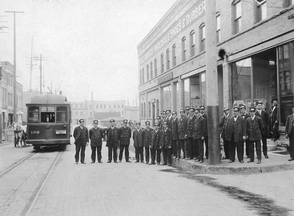 Streetcar conductors pose next to street car #109 on the Oshkosh/Omro line, with the H.C. Roenitz wholesale shoe and rubber company warehouse in the background.