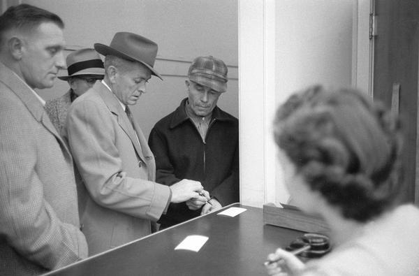 Ed Gein (1906-1984) signing paperwork at the state crime lab where he was brought for lie detector and other tests or at the city jail where he was held overnight.