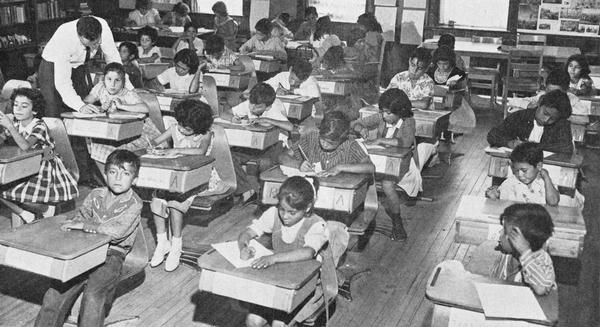 Teacher Richard Vaughan answers a question for one of the six resident children who took the opportunity offered by the 1961 Manitowoc Summer School to learn about the larger world from the migrant children.