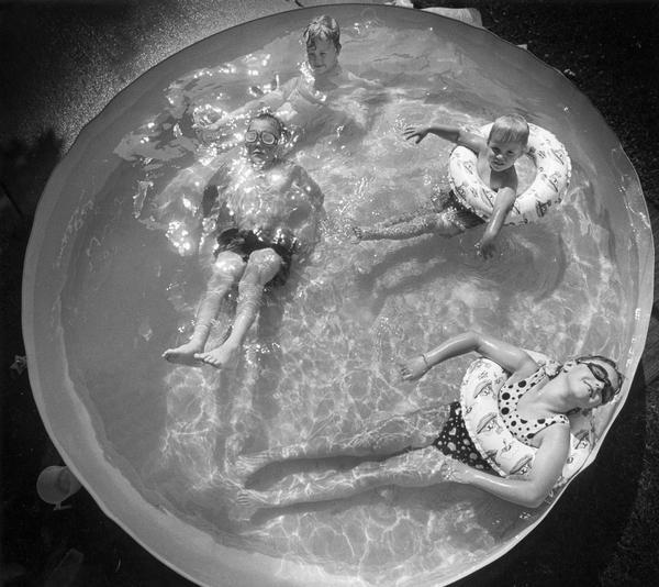 Overhead view of four children relaxing in a wading pool.