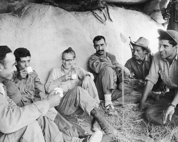 Dickey Chapelle sits and drinks coffee with the FLN Scorpion Battalion Rebels in the Atlas Mountains in Algeria.